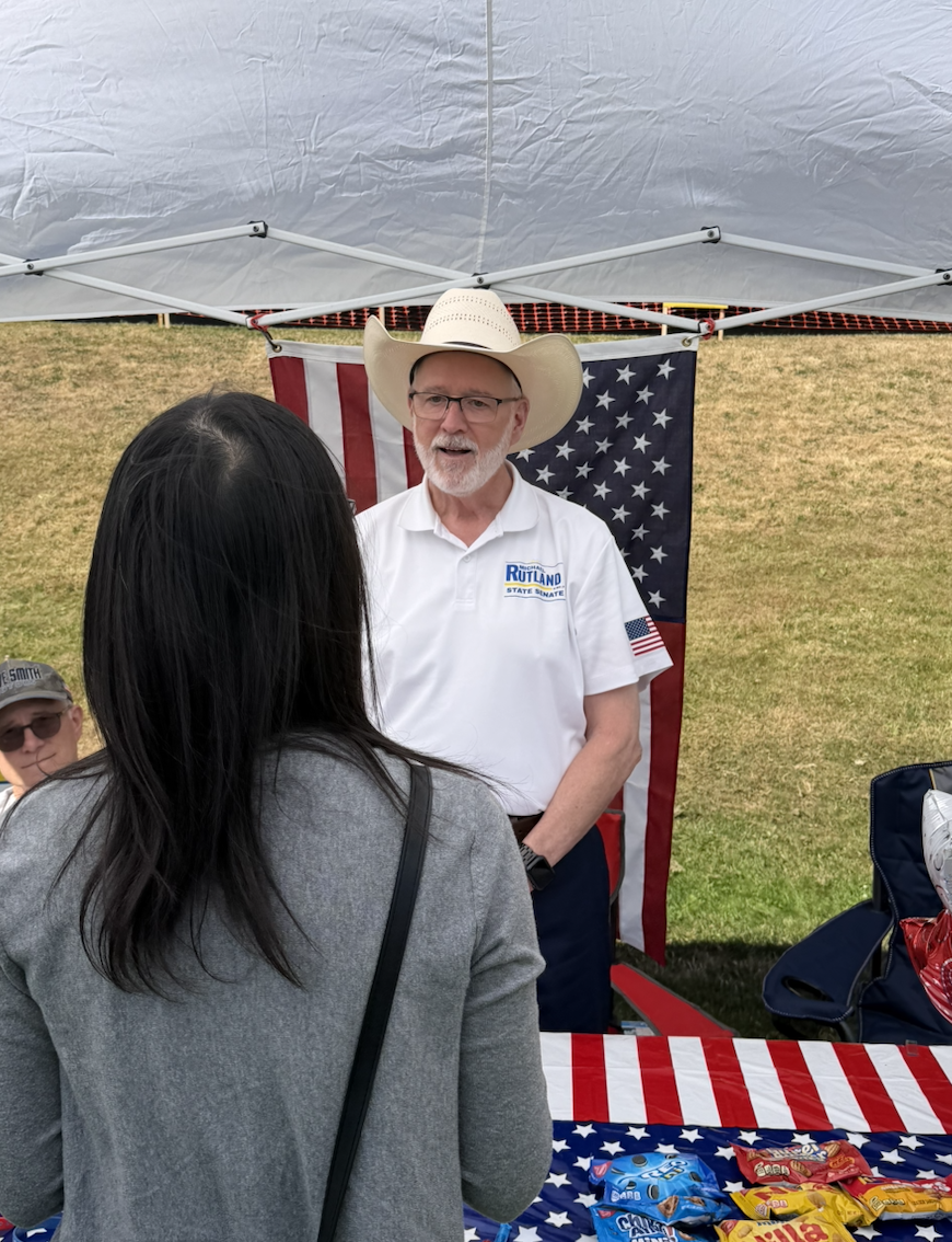 Michael Rutland at his campaign booth with an American flag backdrop