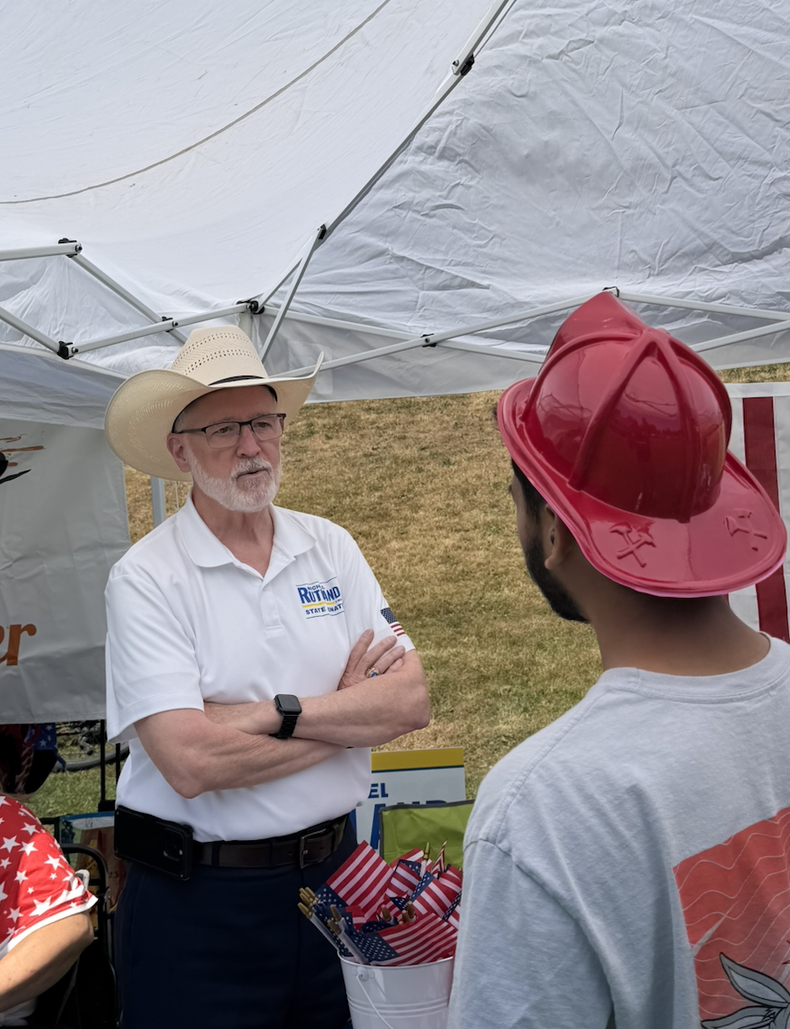 Michael Rutland at a community booth wearing a cowboy hat