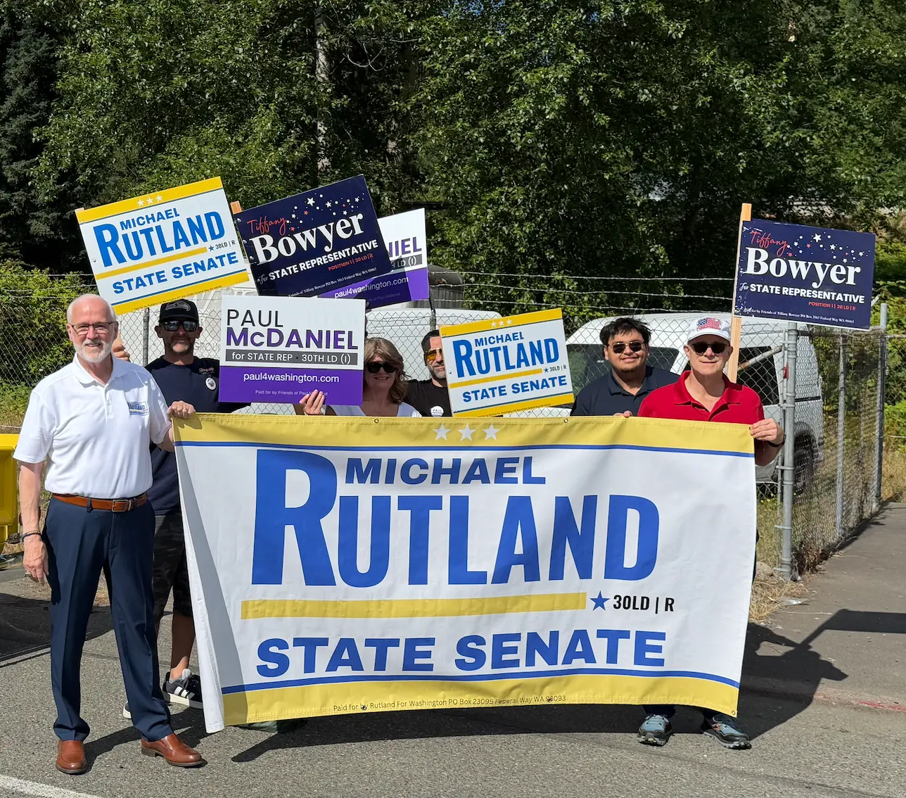 Michael Rutland with supporters holding campaign signs and banner